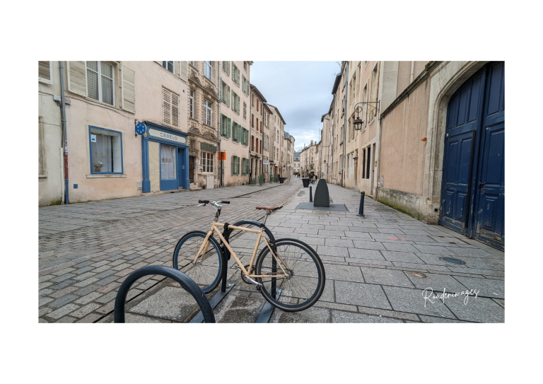 Vélo attaché sur une rue pavée et calme, bordée de bâtiments anciens.
