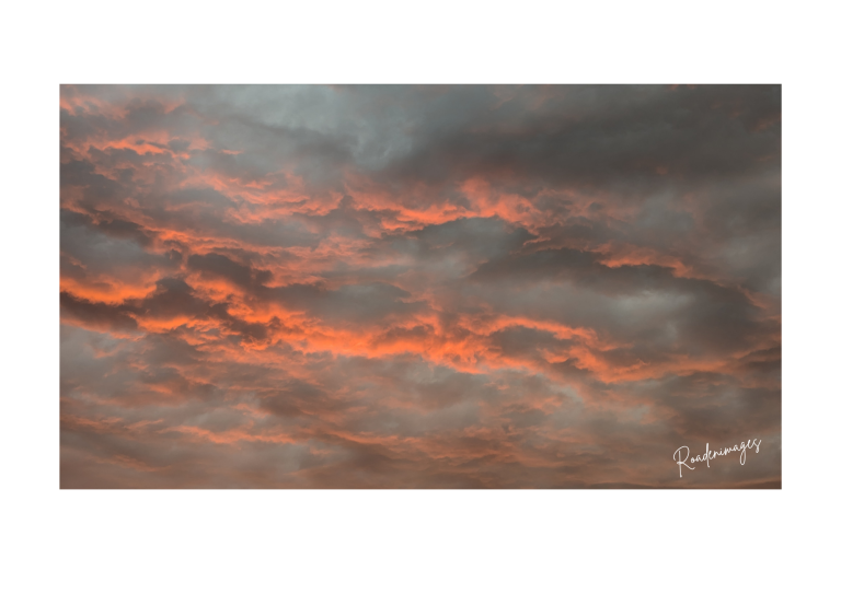 Ciel nuageux aux teintes orange et grises, évoquant un coucher de soleil dramatique.