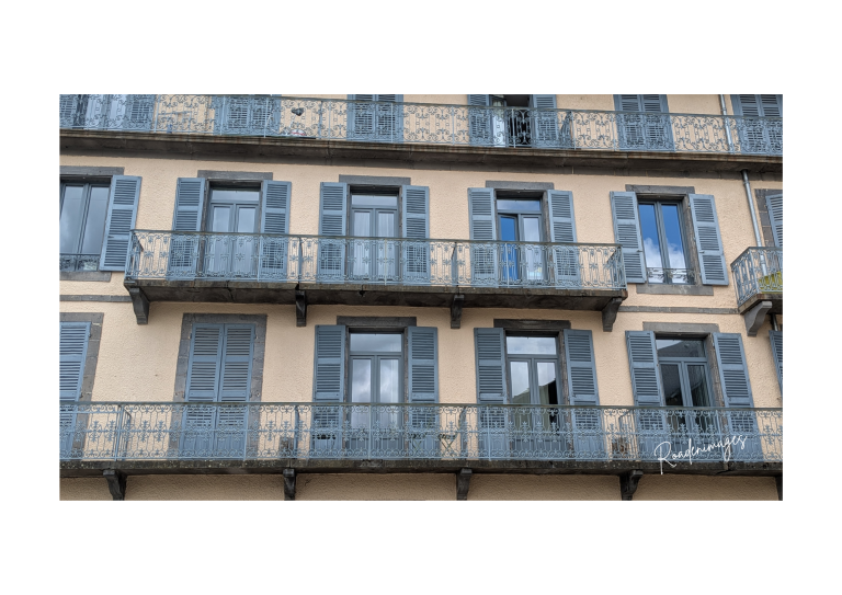 Balcons fer forgé Façade d'immeuble avec balcons en fer forgé et fenêtres à volets bleus.